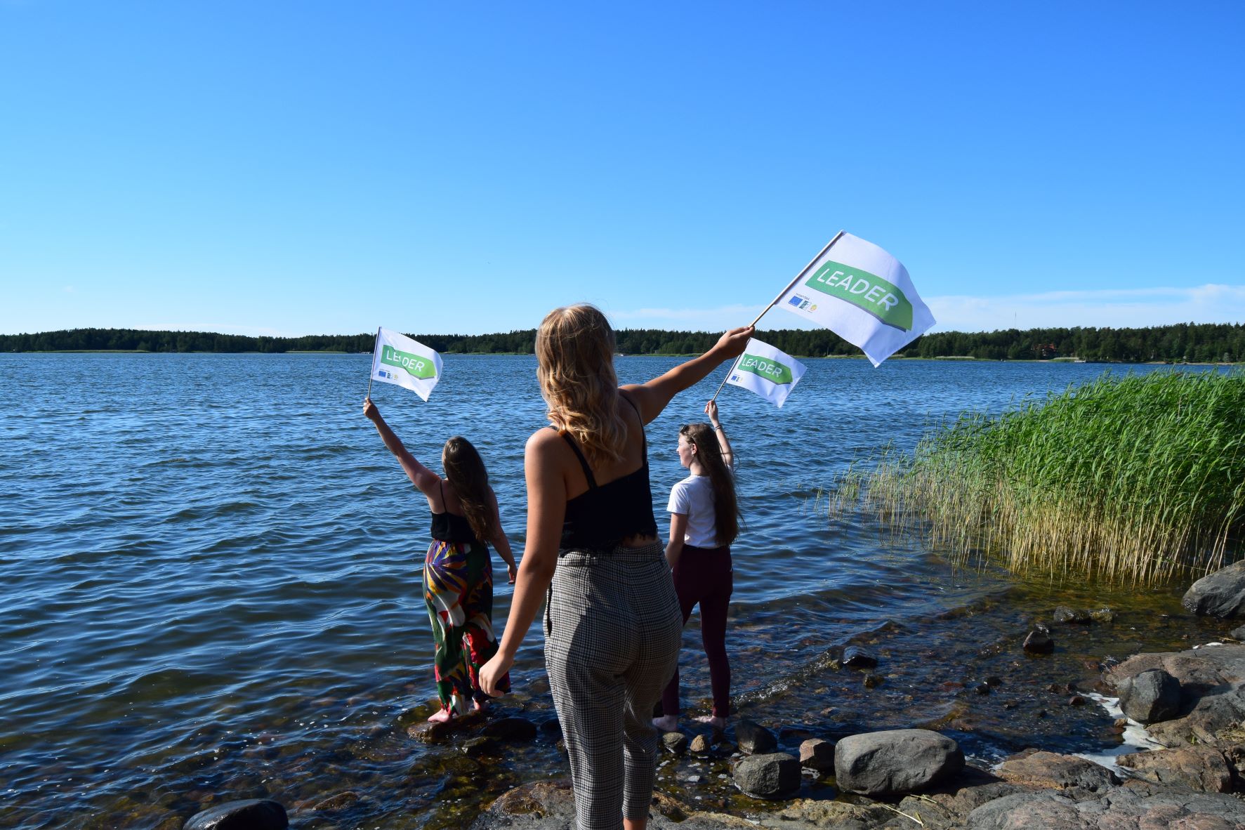 Nuoret heiluttavat lippuja meren rannalla